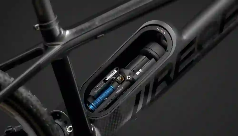 Open downtube storage hatch on a carbon gravel bike frame revealing multi-tool, CO2 inflator, and spare tube inside, illustrating 0.8L capacity