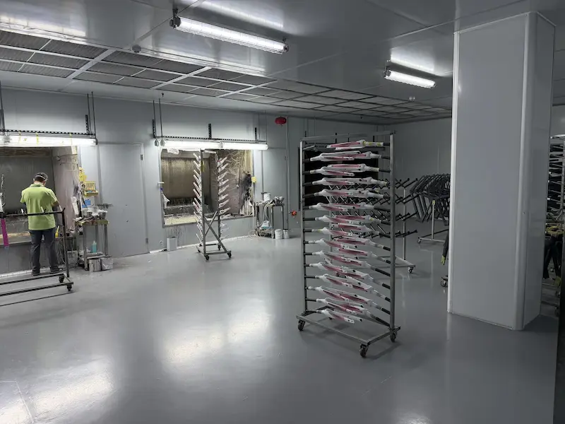 Carbon bike frames on racks inside a paint spray booth